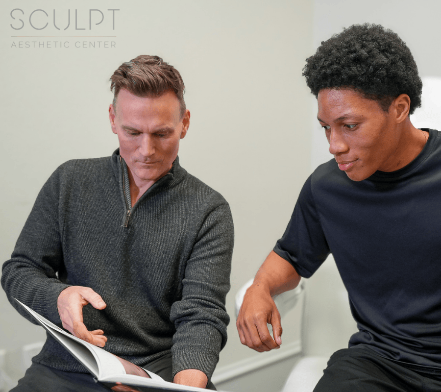 Dr. Beck and a young athletic man sit in a consultation room, discussing peptide injections in Frisco. The patient wants to improve their athletic performance, and shorten their recovery after intense physical activity.