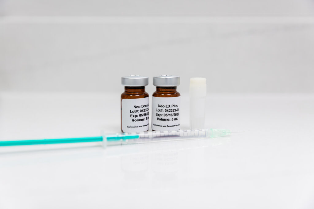 Two medicine vials and a hypodermic needle sitting on a white counter represent stem cell and exosome therapy at SCULPT's men's wellness center in Frisco, TX.