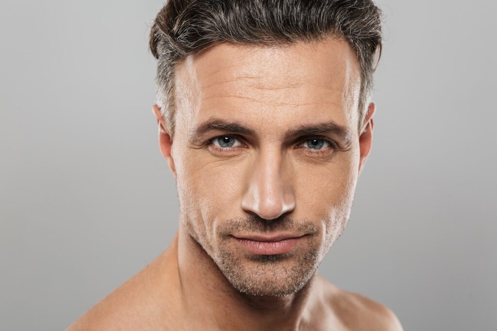 Front-facing handsome man in his late 40s facing the camera. His eyes seem refreshed and youthful after blepharoplasty in Frisco, TX.